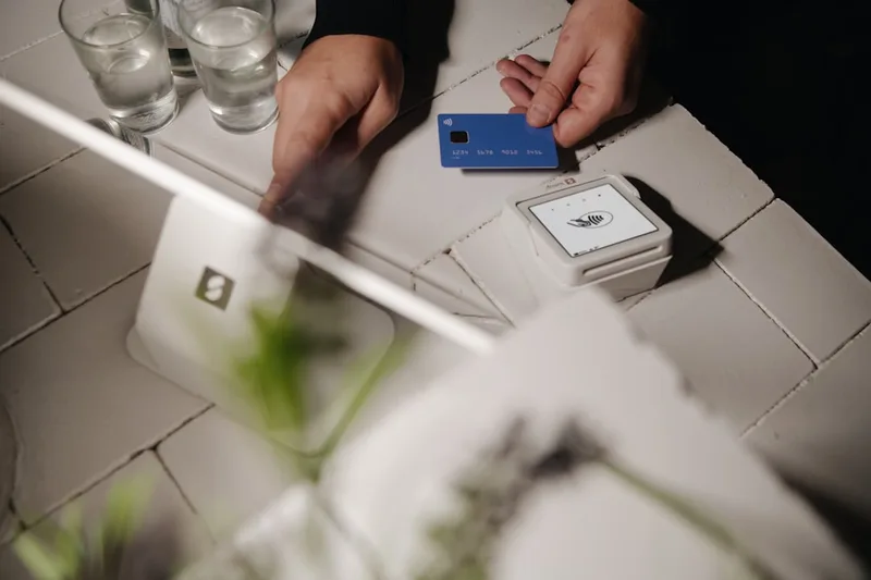 casal brasileiro usando cartão no café com consciência sobre “Erros caros que brasileiros cometem com anuidade cartão” com notebook com plan