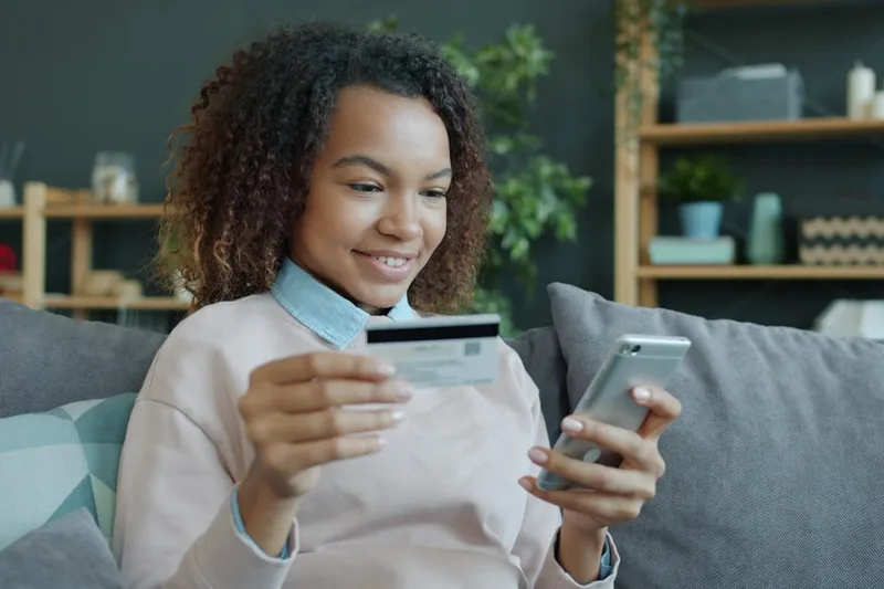 estudante universitário brasileiro guardando cartão na carteira sobre “Estratégia prática: de limite consciente a score Serasa” com app de f