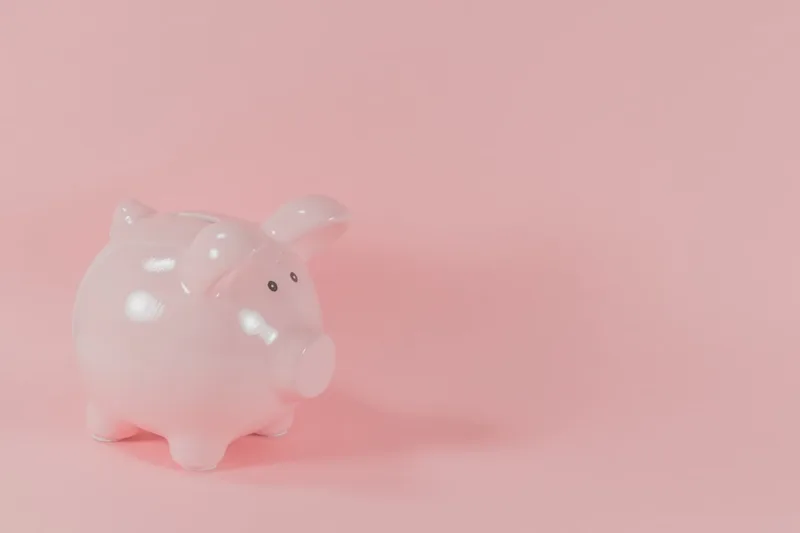 profissional liberal brasileiro estudando livro de finanças sobre “Estratégia prática: de família a hábitos” com cofrinho e moedas em cozinh