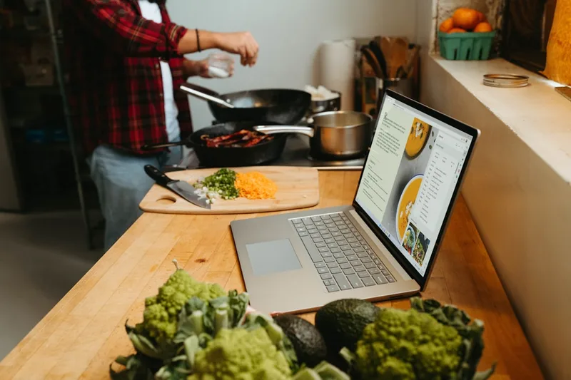 casal brasileiro cozinhando refeição econômica sobre “O que é meal prep (e o que não é)” com carrinho de supermercado em sala de estar simpl