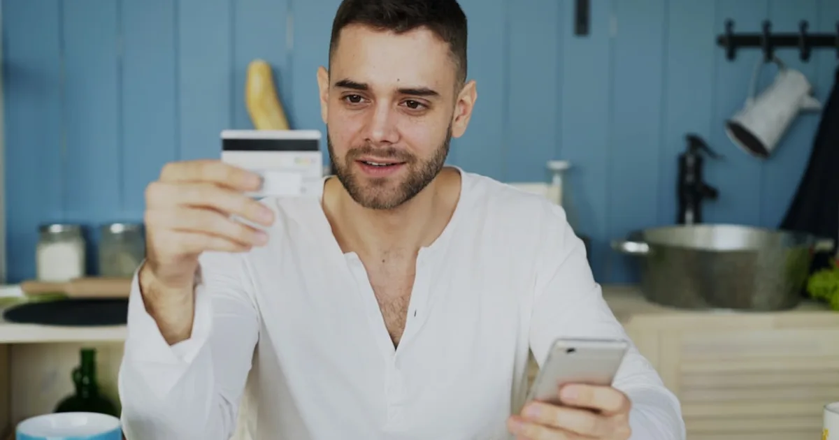 pessoa brasileira adulta ilustrando fatura do cartão em home office com planta e luz natural (Como Organizar a Fatura do Cartão e Nunca Paga
