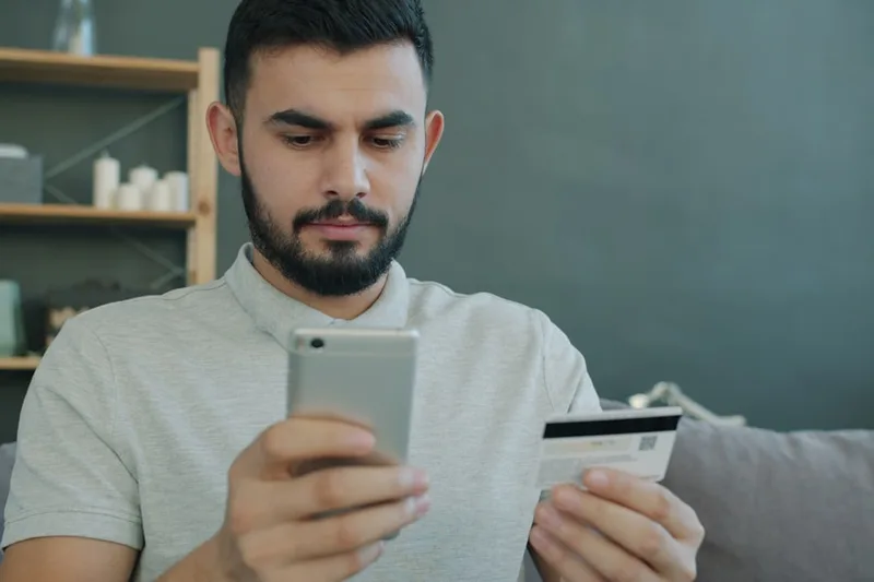casal brasileiro anotando compras do mês sobre “Por que fatura do cartão muda o fim do mês no Brasil” com calculadora e cartão em bancada da