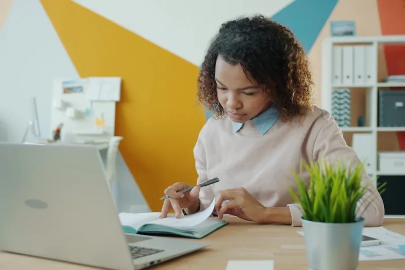 pessoa brasileira adulta organizando recibos e notas sobre “Erros caros que brasileiros cometem com restituição IR” com notebook com program