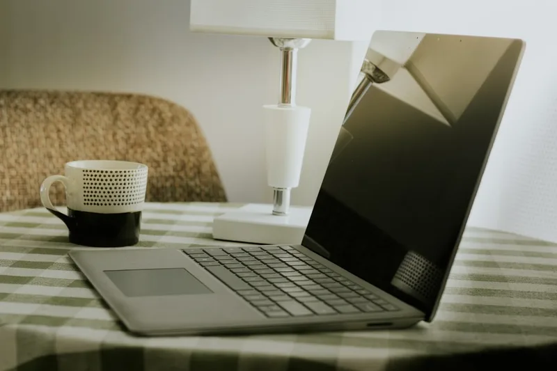 mãe brasileira conversando sobre FGTS sobre “O que é Selic bolso (e o que não é)” com caneca e notebook em sala de estar simples com sofá (O
