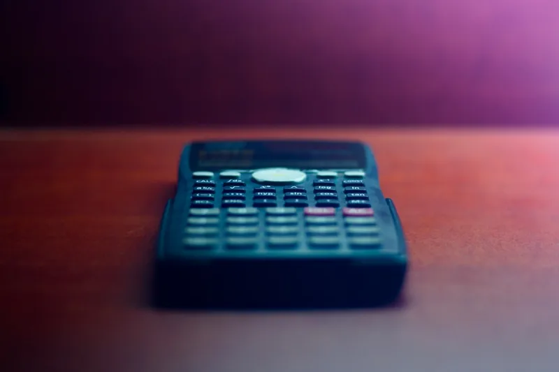 microempreendedora brasileira checando app de notícias sobre “Exemplo numérico com R$ 410,00 por mês” com jornal e café em quarto de estudo
